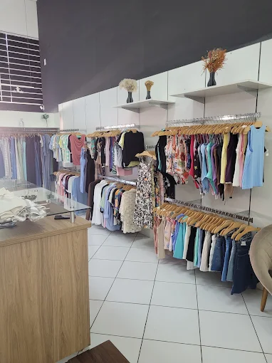 Interior da loja com araras de roupas organizadas por cor